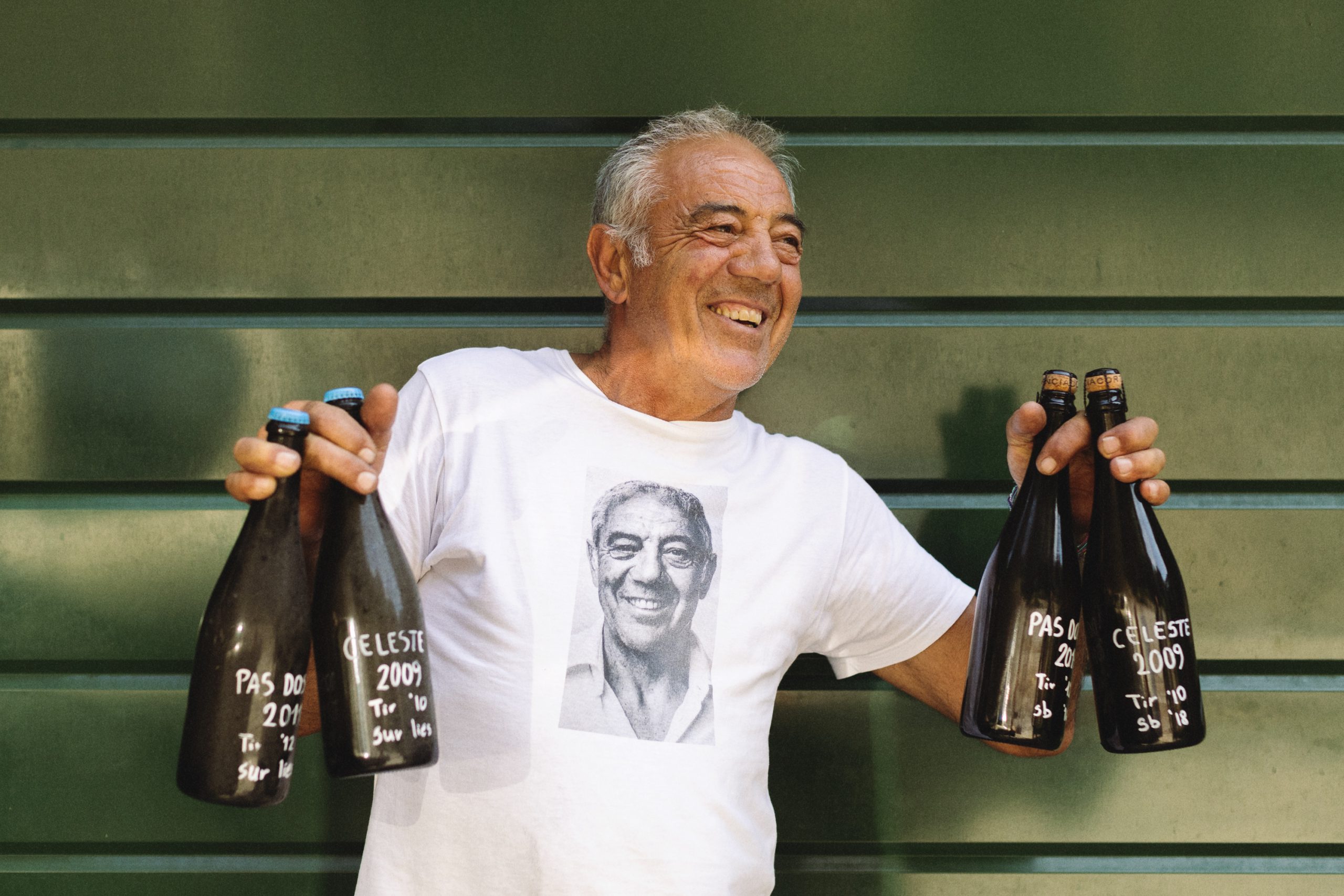 Uomo sorridente che tiene in mano bottiglie di Franciacorta Pas Dosé e Celeste 2009 durante il Festival della Franciacorta 2024 a San Cristoforo